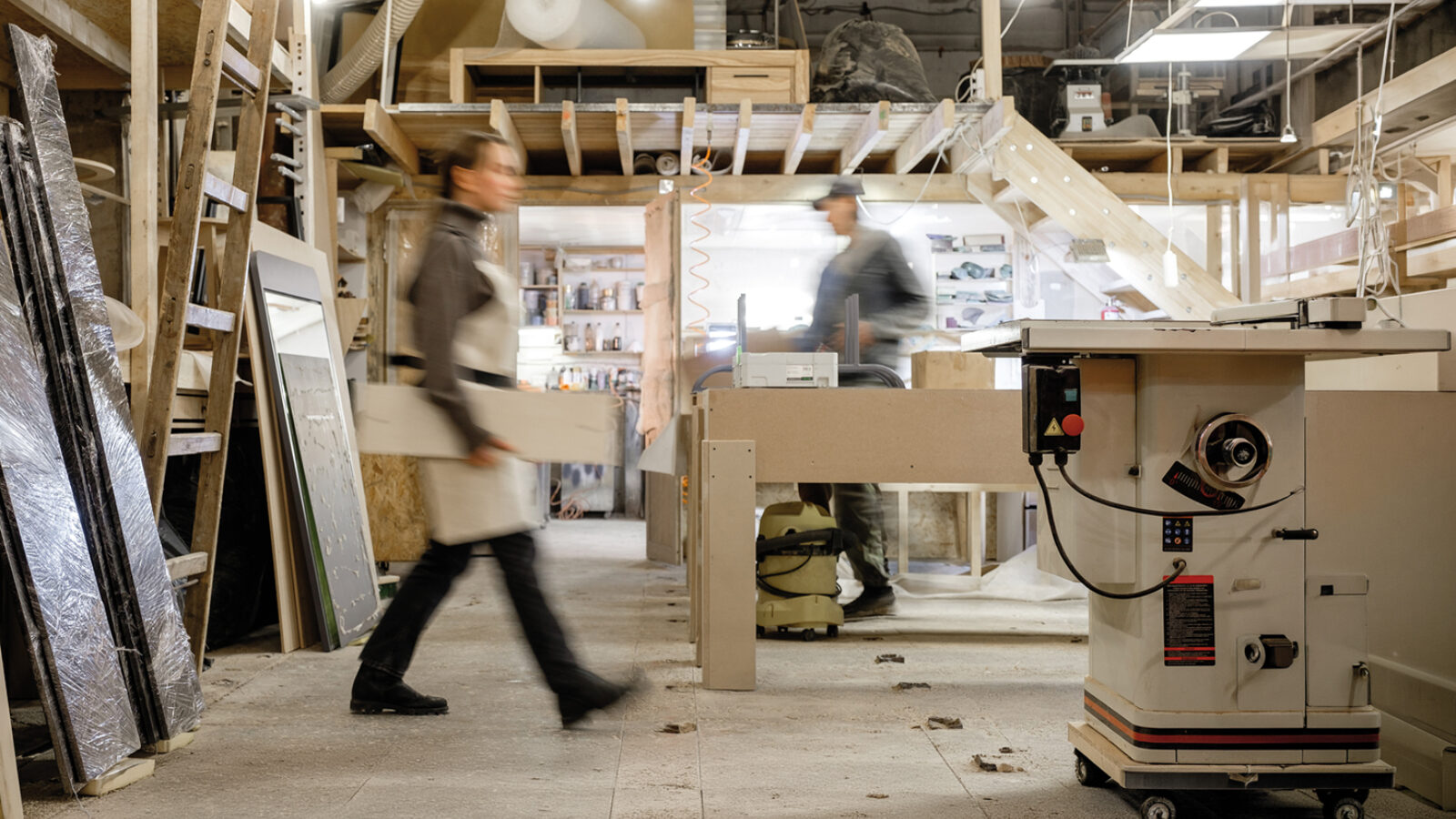 Exposure photography two unidentified young employees of small woodworking and furniture industry working on new furniture collection. Concept of own small successful production