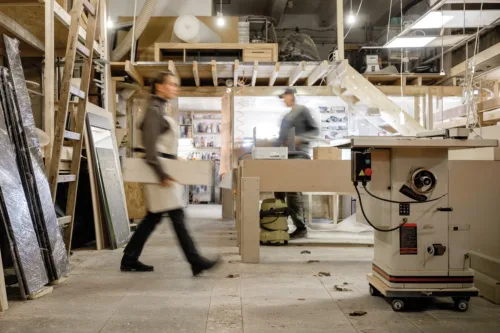 Exposure photography two unidentified young employees of small woodworking and furniture industry working on new furniture collection. Concept of own small successful production